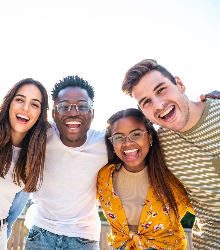 Low angle view of a happy group of multiracial friends looking at camera, enjoying outdoors. Multiethnic cheerful young people. High quality photo