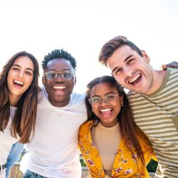 Low angle view of a happy group of multiracial friends looking at camera, enjoying outdoors. Multiethnic cheerful young people. High quality photo